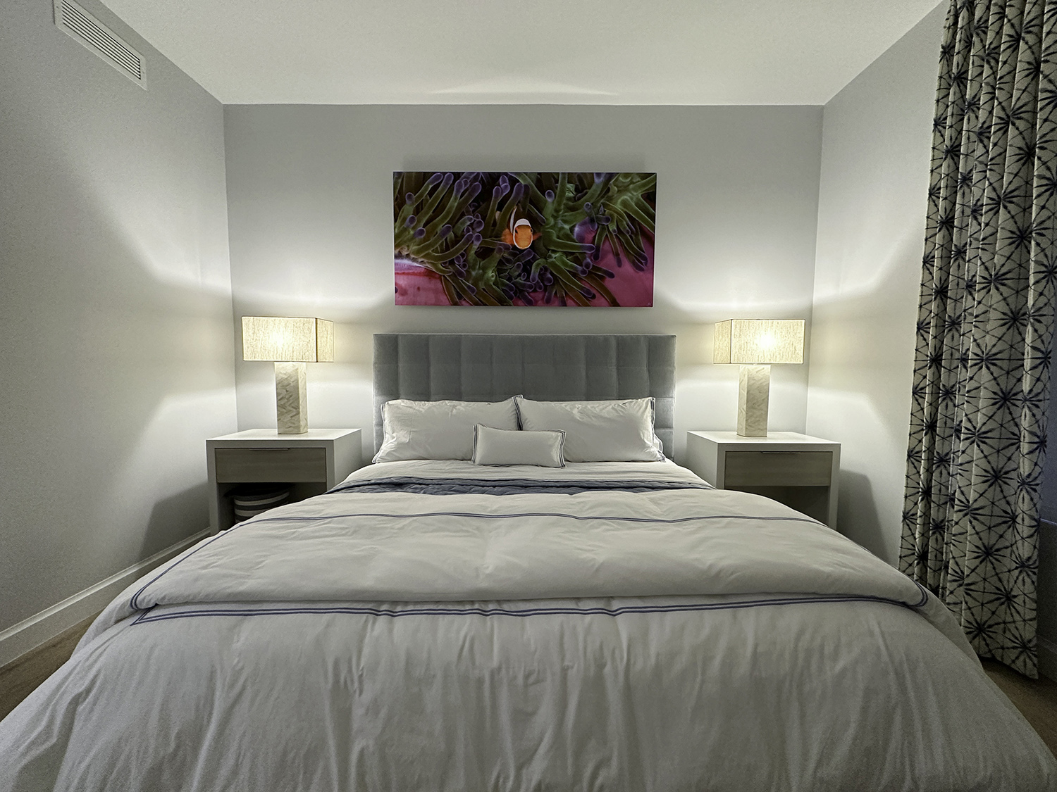 large photograph of a clownfish in its pink and purple and green anemone hanging over a bed