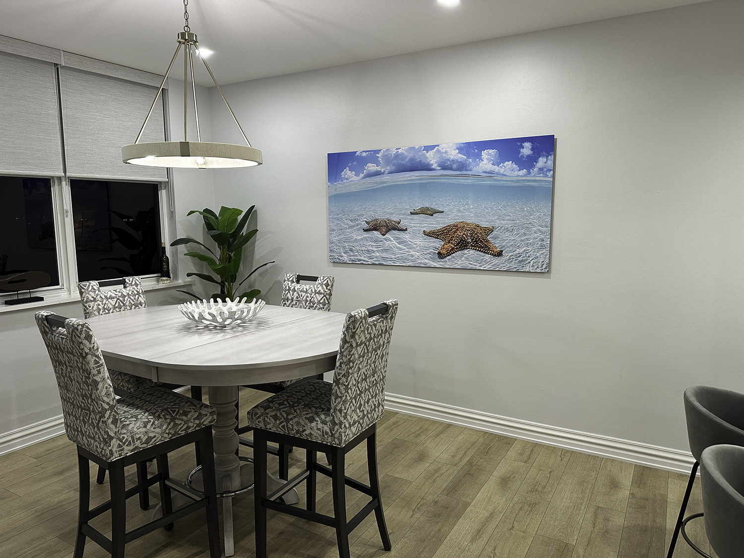 large art underwater photograph of three starfish in shallow water over white sand, displayed in a dining room