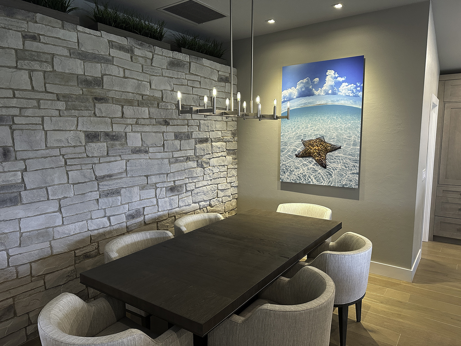 large art underwater photograph of a starfish in shallow water over white sand, displayed above a dining room table