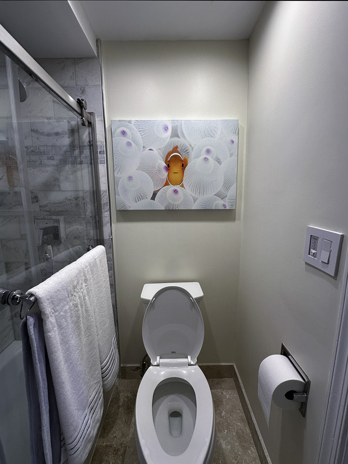 fine art underwater photograph of a clownfish in a white anemone, displayed in a bathroom