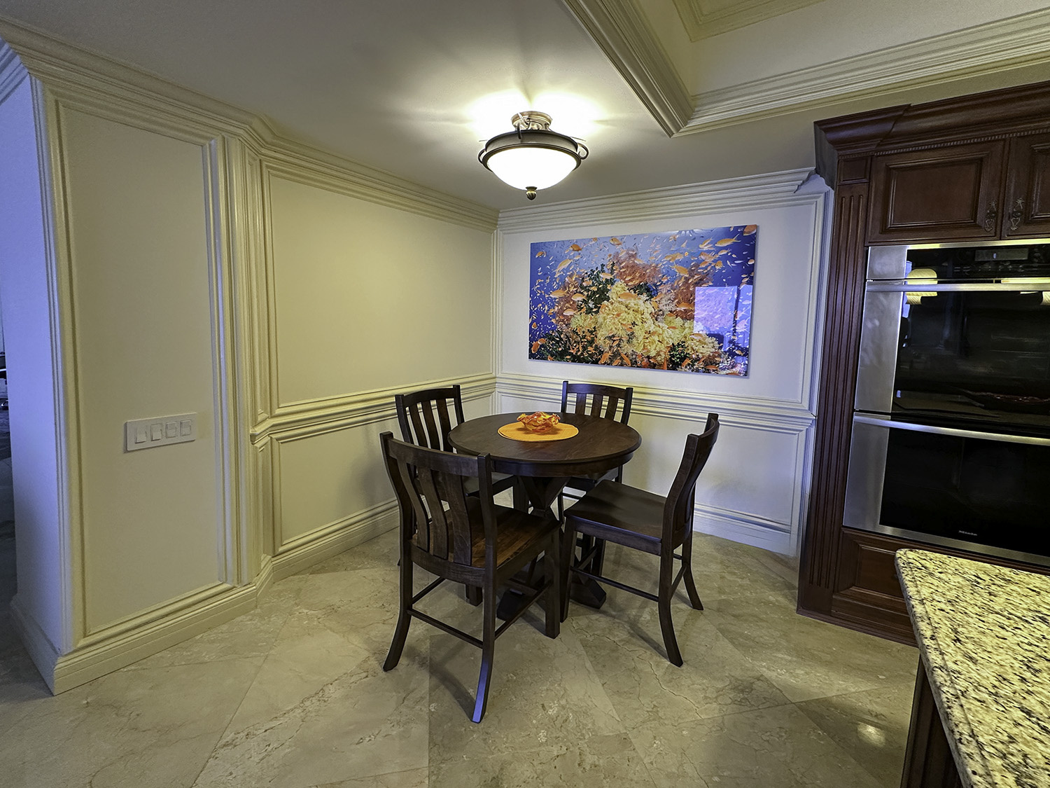 Riot 70x35 large fine art underwater photograph of a school of orange fish on a coral reef, displayed in a dining room